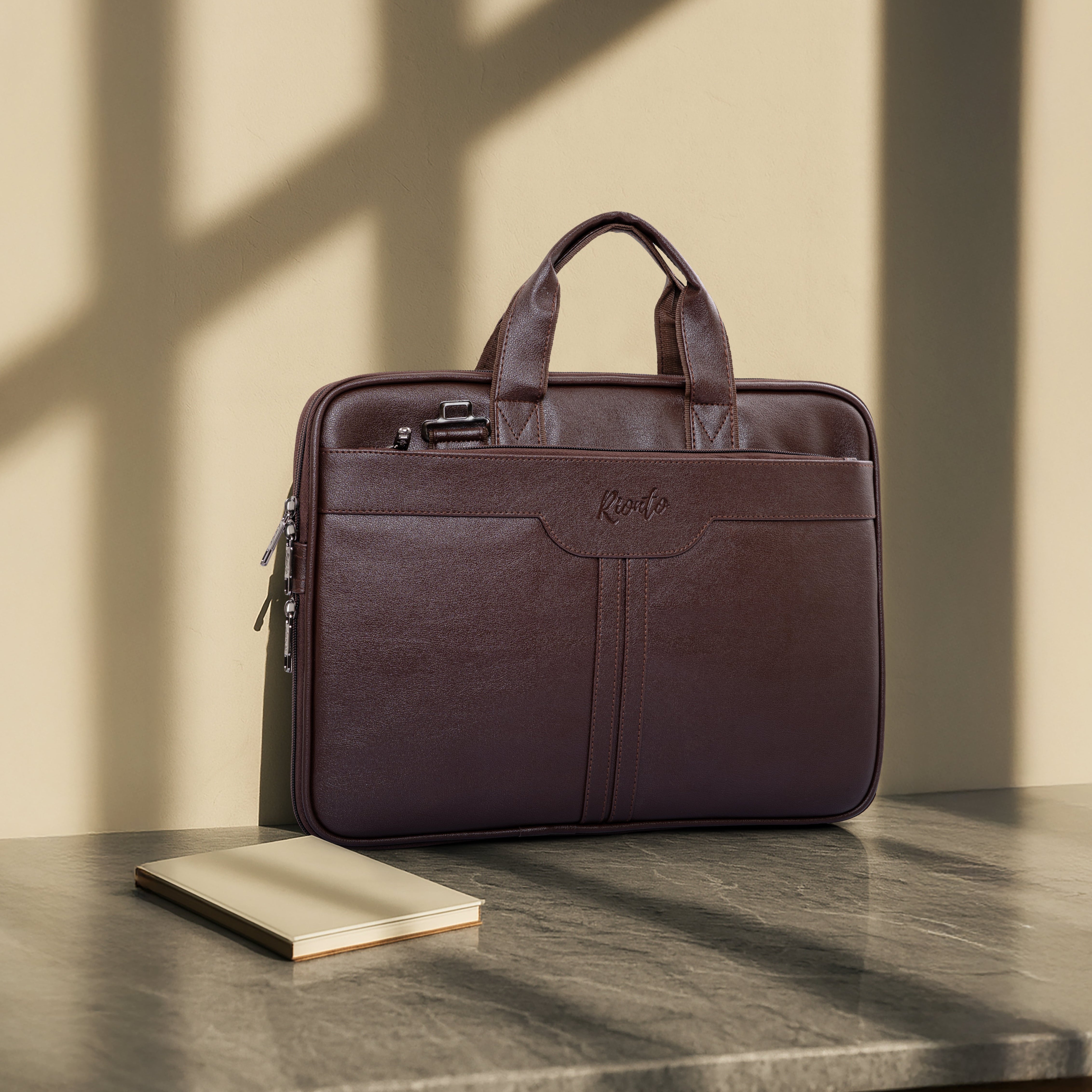 Brown leather briefcase on a marble surface with a neutral wall background